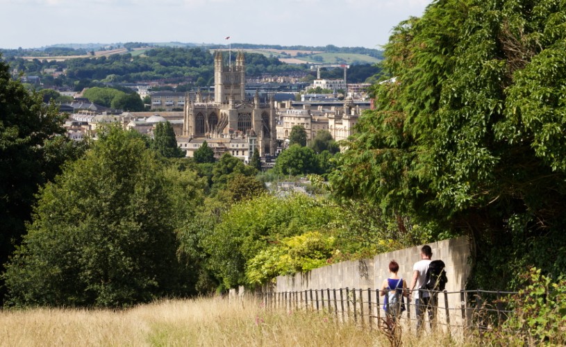 Two people walking with view of Bath Abbey